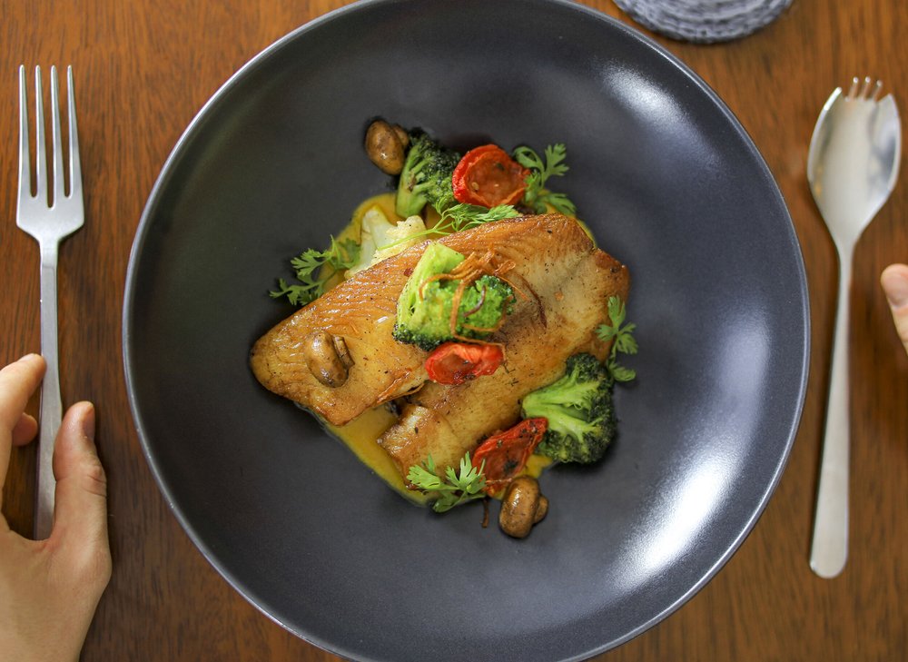 A Nyurah dish with golden fish, seasonal vegetables and carefully composed garnishes